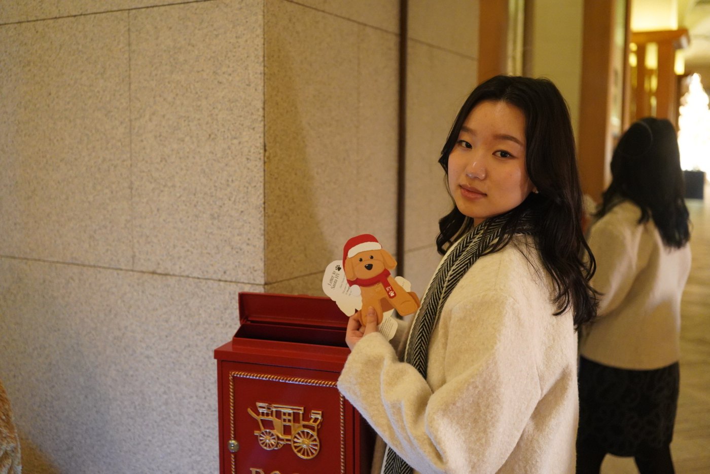 Rebecca holding a gingerbread toy beside a red mailbox