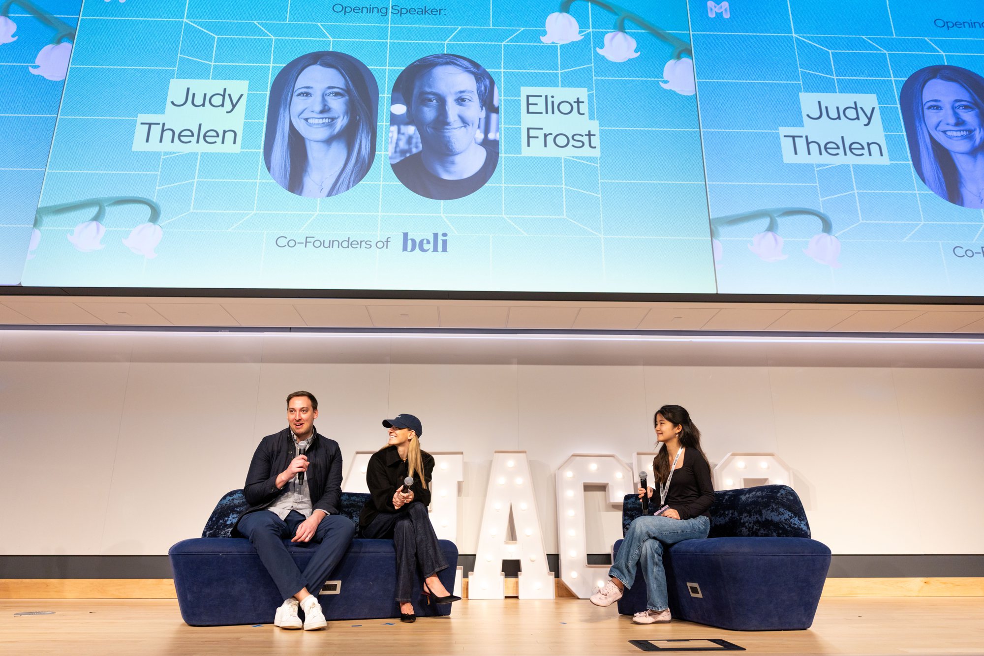 The co-founders of Beli speaking on stage in front of the opening speaker slide