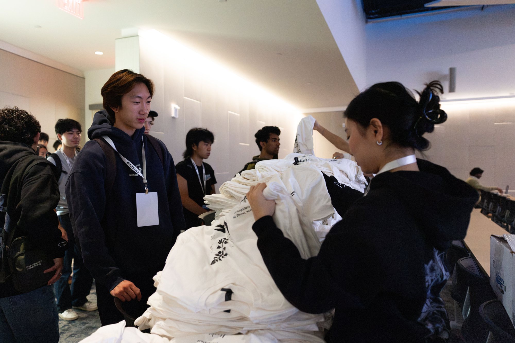 Rebecca handing out MHacks t-shirts to a line of hackers